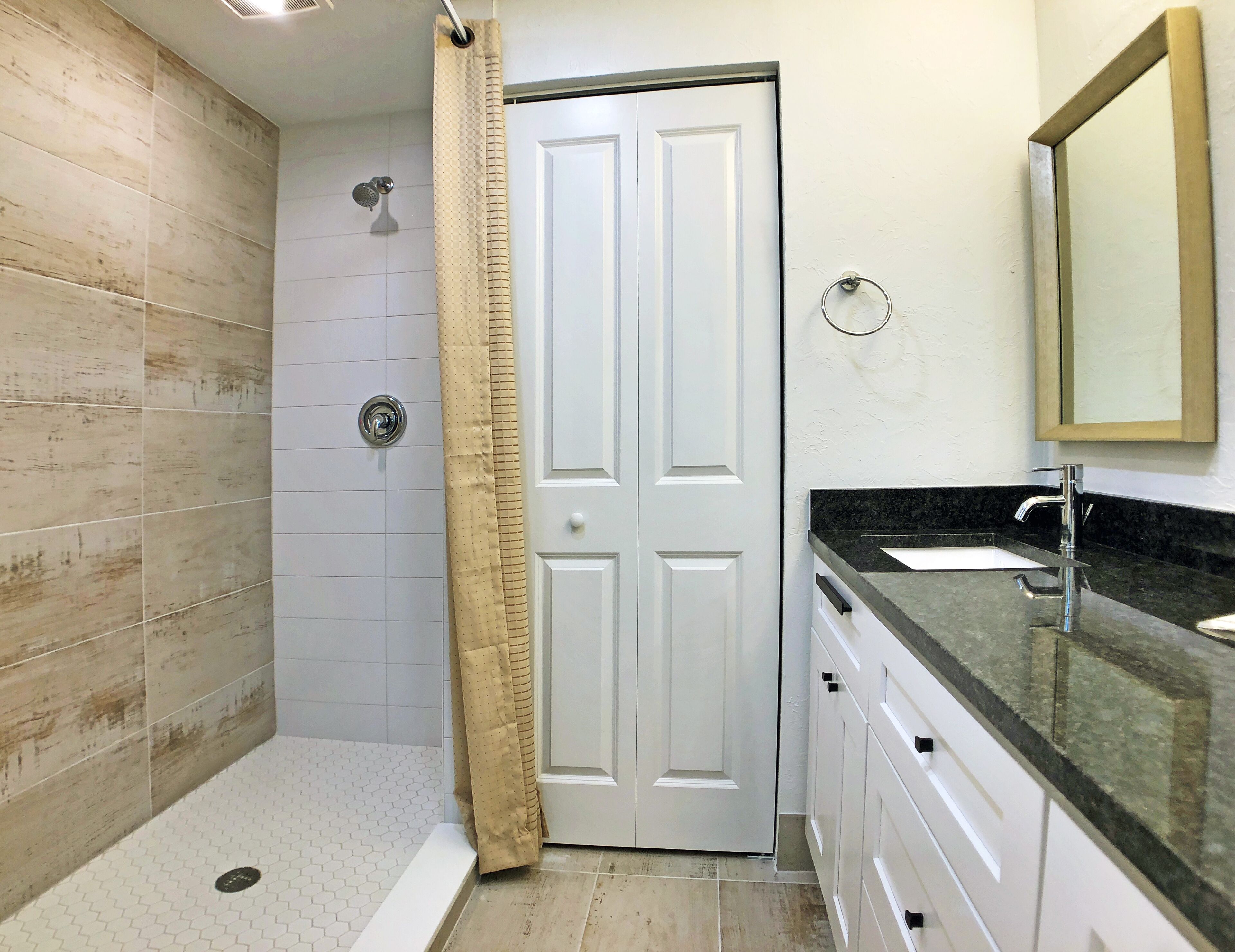 Een badkamer met een douche, een wastafel en een deur.