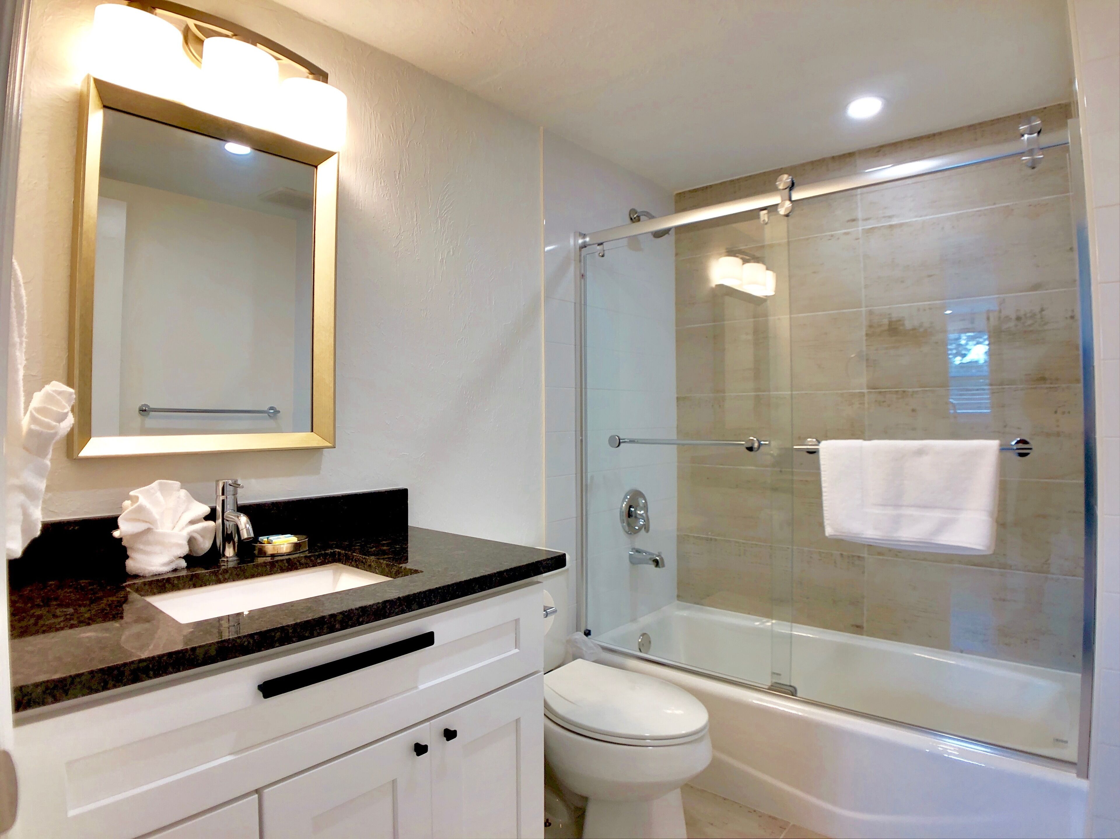 Un baño moderno con ducha acristalada, inodoro blanco y tocador con espejo y lavabo.