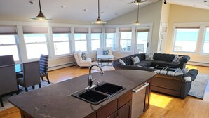 A modern kitchen with a central island, a dining area with a table and chairs, and a seating area with a sofa and chairs. - Luxurious Beachfront House - spectacular ocean views - w/ indoor elevator (Old Orchard Beach)