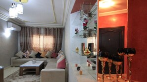Uma sala de estar com sofá, mesa de centro e aparador de vidro com objetos decorativos.
