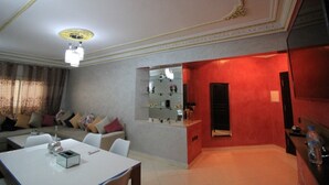 Uma sala de estar moderna com área de jantar, uma parede de destaque vermelha e uma estante embutida.