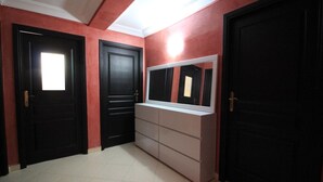 Um corredor com três portas pretas, um aparador branco e um espelho grande.