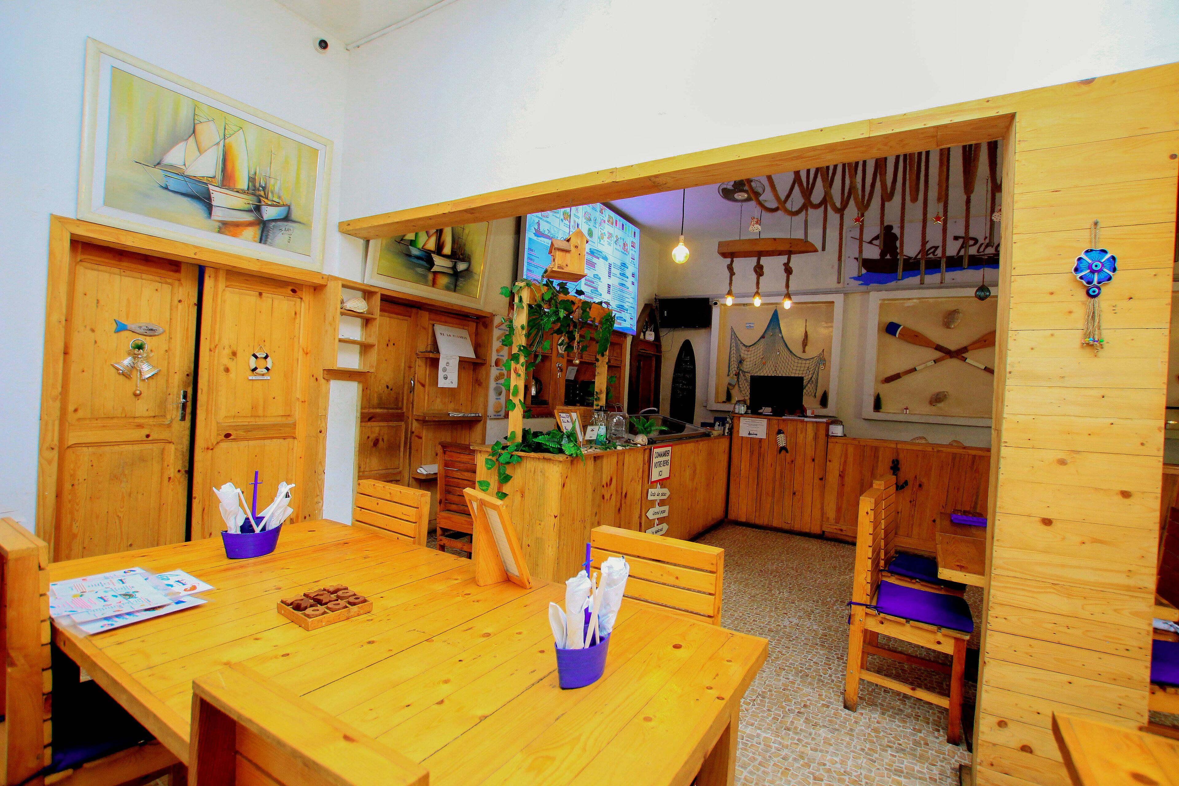 Un comedor de madera con una mesa dispuesta para dos personas, un sujetapapeles azul y un menú sobre la mesa.