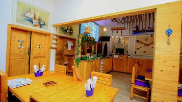 Un comedor de madera con una mesa dispuesta para dos personas, un sujetapapeles azul y un menú sobre la mesa.