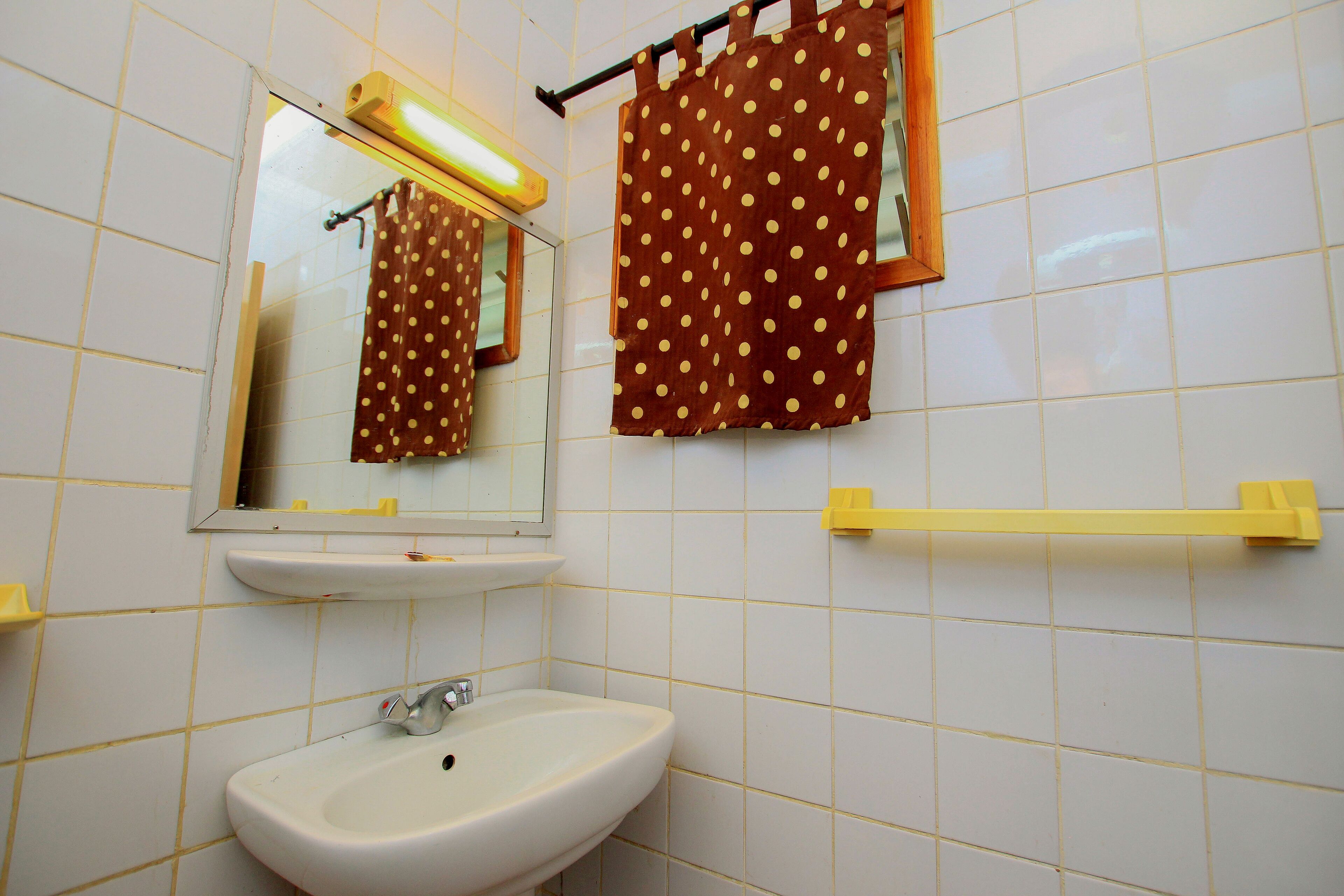 A bathroom with a white sink, mirror, and a towel rack with a brown towel.