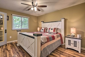A bedroom with a bed, a nightstand, a ceiling fan, a window, and a door. - 1 Mi to Parkway! Flat-Access Pigeon Forge Condo (Pigeon Forge)