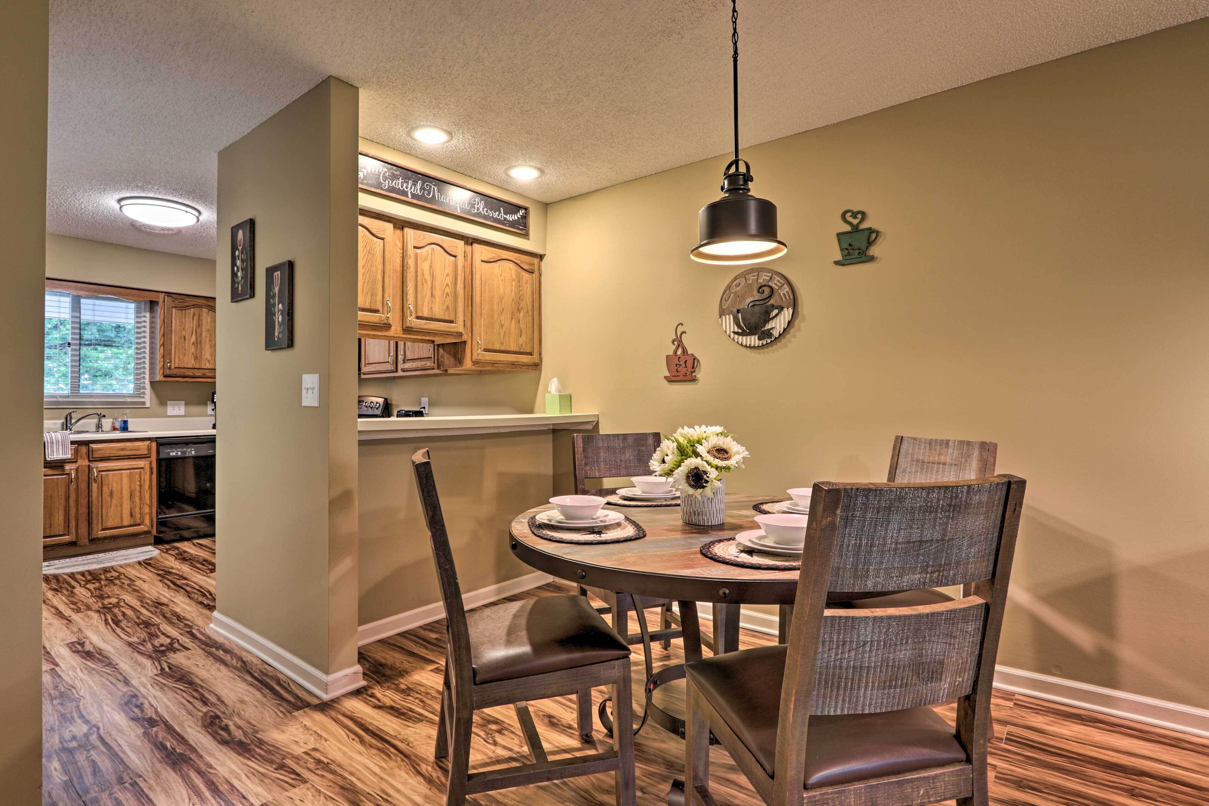 A dining area with a round table, chairs, and a hanging light fixture.