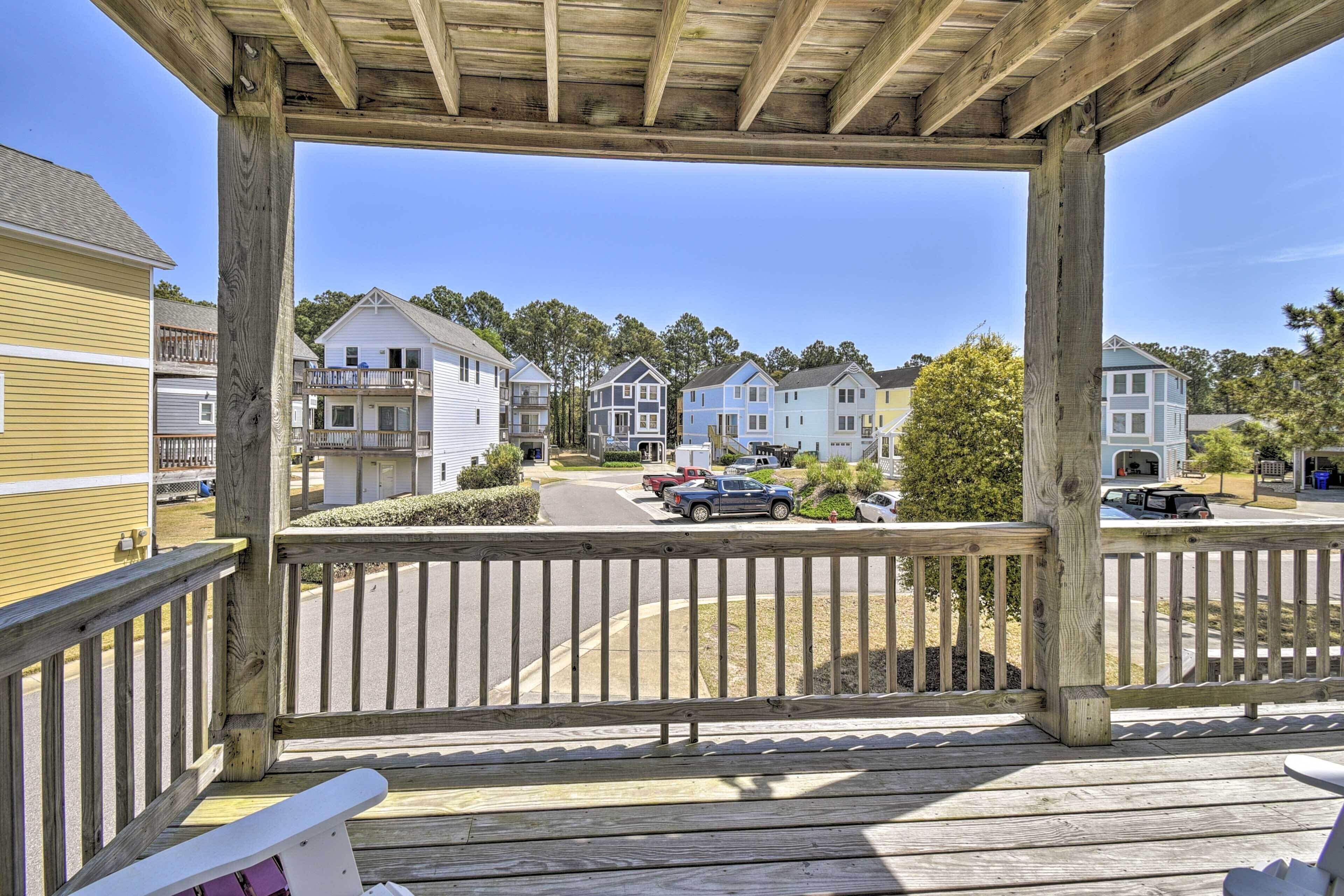 Une terrasse en bois offrant une vue sur un quartier résidentiel, avec des maisons et des voitures garées.