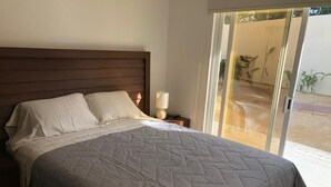 Ein Schlafzimmer mit Bett, Nachttisch und Fenster mit Blick ins Freie.