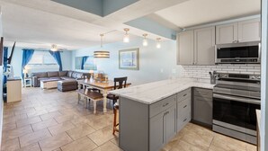 A modern kitchen with grey cabinets, a marble countertop, and stainless steel appliances. - Make memories on the beach! Clean 3bd/2bth condo! (Panama City Beach)