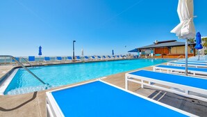 A swimming pool with blue lounge chairs and umbrellas, a lifeguard tower, and a building with a sign that reads "KIRKLAND". - Make memories on the beach! Clean 3bd/2bth condo! (Panama City Beach)