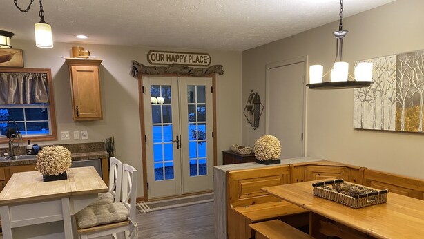 A cozy kitchen with a wooden bench, a dining table, and a sign that reads "OUR HAPPY PLACE".