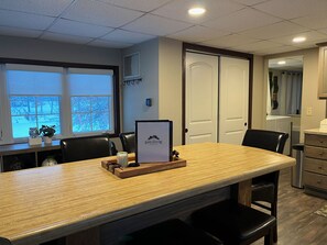 A modern kitchen with a wooden island, black chairs, and a framed sign on the island. - Cozy Chic Cabin on Private 10-acre Lake. (Independence)