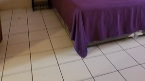 Una stanza con un letto, un comodino e un pavimento piastrellato.