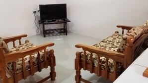 Una stanza con un divano in legno, un televisore su un mobile e un armadietto bianco.