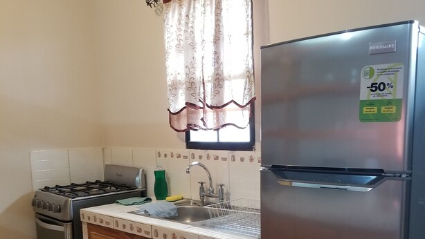 Una cucina compatta con frigorifero, fornello, lavello e pensili in legno.