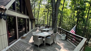 Um deck de madeira com móveis de exterior, uma mesa de jantar e uma bandeira.
