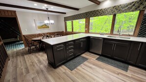 Cozinha moderna com armários escuros, bancada de mármore e uma grande janela com vista para o verde.