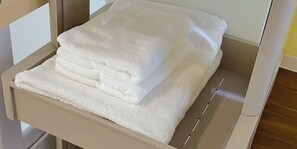 A stack of white towels on a beige tray in a room. - Hotel Shion no umi (Miyakojima)