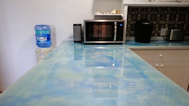 A kitchen with a blue-tinted countertop, a microwave, a toaster, and a water dispenser. - Hidden by beautiful palm and flamboyant trees but close to restaurants & stores  (Christiansted)