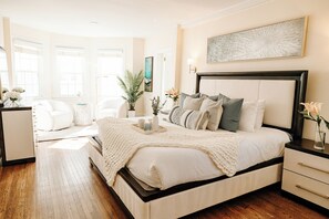 Un dormitorio con una cama grande, una mesita de noche, una silla y un mueble auxiliar.