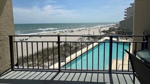 Un balcone con vista sulla spiaggia e su una piscina.