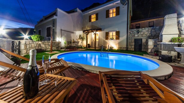 A swimming pool with wooden deck chairs and a bottle of champagne. - Villa Ljilja (Grizane)