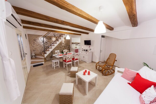 A spacious living area with a dining table, chairs, a sofa, and a wooden rocking chair. A staircase leads to an upper level. - Villa Ljilja (Grizane)
