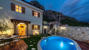 A house with a swimming pool, stone wall, and a patio with a table and chairs. - Villa Ljilja (Grizane)