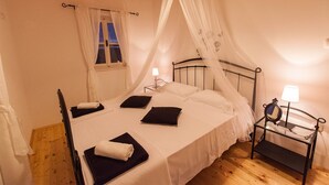 A single bed with a canopy, bedside table with a lamp, and a window with curtains. - Villa Ljilja (Grizane)
