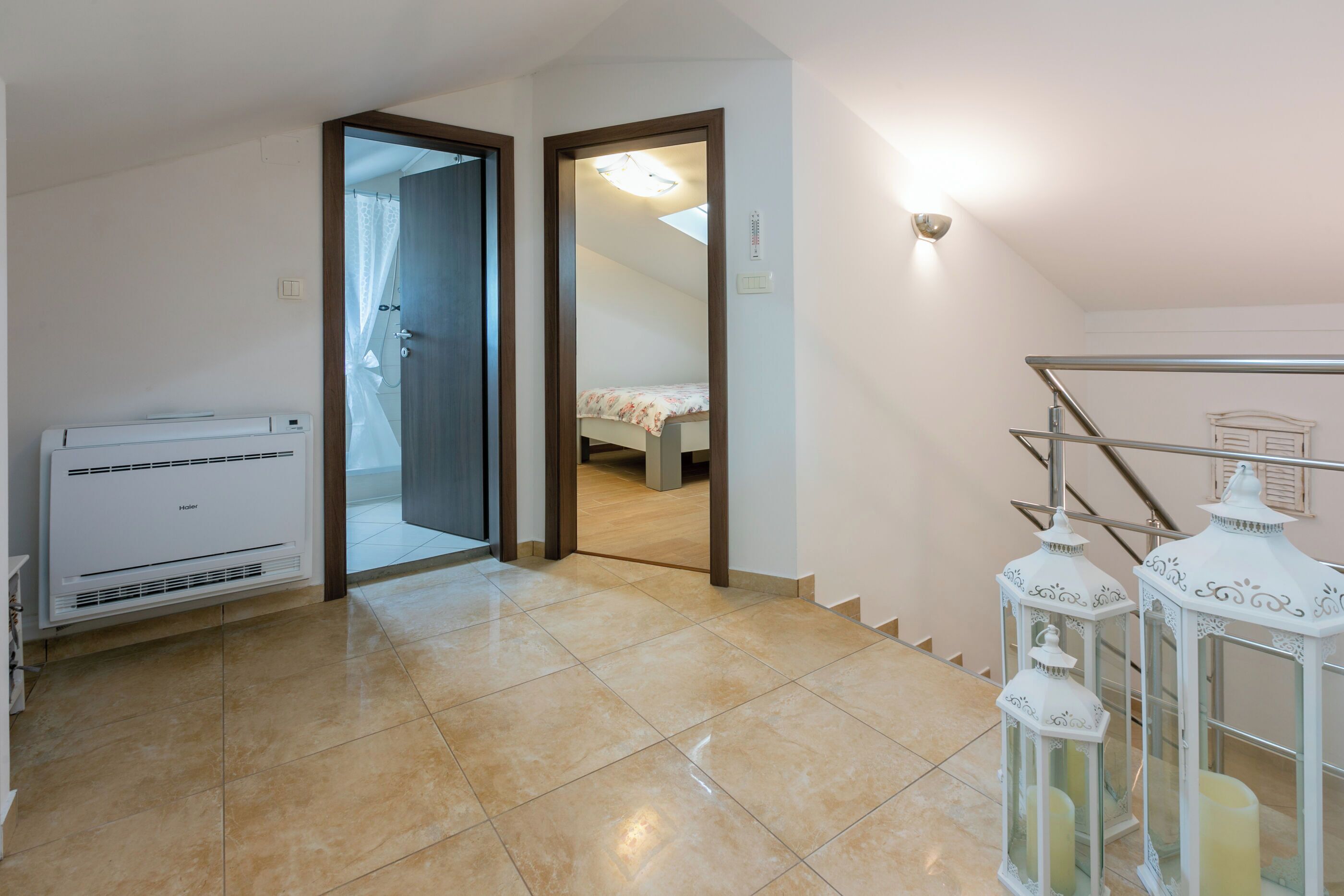 A hotel room with a bed, a bathroom with a shower, a heater, and a staircase.