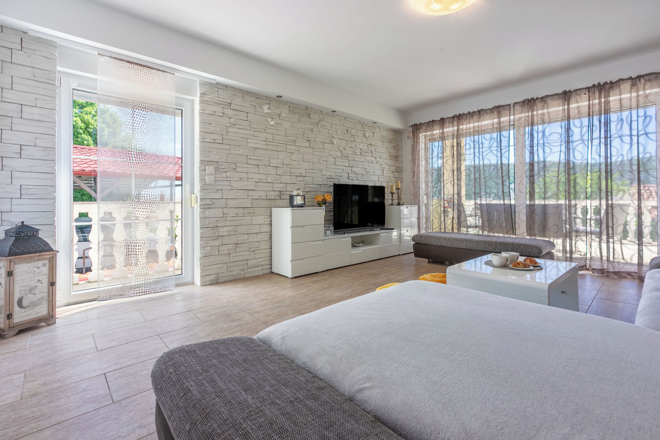 A modern living room with a large bed, a TV, a sofa, and a coffee table.