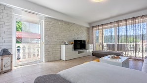 A modern living room with a large bed, a TV, a sofa, and a coffee table. - Villa Marta (Grizane)