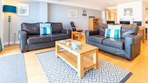 A modern living room with two leather sofas, a wooden coffee table, and patterned rugs. - Fistral Beach Apartment 3 -  a fistral beach that sleeps 4 guests  in 2 bedrooms (Newquay)