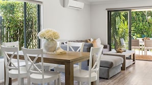 Ein modernes Wohnzimmer mit Essbereich, großen Fenstern und Blick auf Grünflächen.