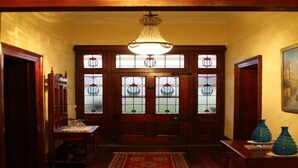 A wooden entryway with a chandelier, stained glass windows, and a red patterned rug. - Leconfield House, luxury and heritage hotels in Pokolbin Hunter Valley (Leconfield)