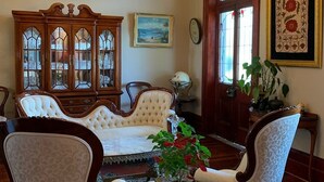 A traditional living room with a chandelier, a large wooden cabinet, and two upholstered chairs. - Leconfield House, luxury and heritage hotels in Pokolbin Hunter Valley (Leconfield)