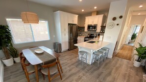 A modern kitchen with white cabinets, stainless steel appliances, and a central island with bar stools. - *Cali King Bed * Bright Natural Light * Tall Ceilings * Full Kitchen * Balcony (San Diego)