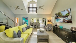 A spacious living area with a high ceiling, a yellow sofa, a dining table, and a kitchen in the background. - **MAYA’S SECRET TREASURE** Pool & Balcony + Last Key White Glove Service... (Key West)