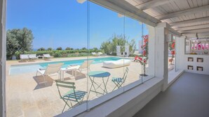 Ein moderner Poolbereich mit Liegestühlen und einer verglasten Terrasse.