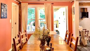Un comedor con una mesa de madera, sillas y un jarrón con flores.