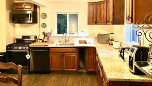 Una cocina con armarios de madera, estufa de acero inoxidable, microondas y cafetera.