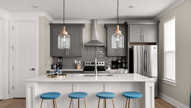 A modern kitchen with a central island, bar stools, stainless steel appliances, and pendant lighting. - Duke9 ~ Private Penthouse Rooftop ~ Newly Redesigned Interior ~ 8 Min to Downtown and Broadway (Nashville)
