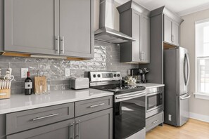 A modern kitchen with grey cabinetry, a stainless steel range, a built-in oven, and a refrigerator.