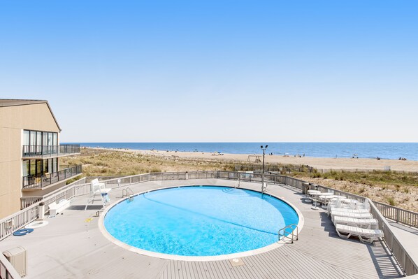 Enjoy a relaxing space with a clear view of the ocean from our rooftop pool area, surrounded by lounge chairs and a table.