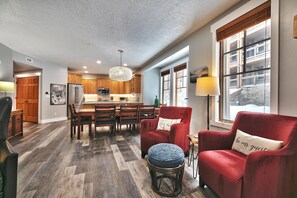 Un vaste espace de vie comprenant un fauteuil rouge, un pouf et une table à manger avec des chaises.