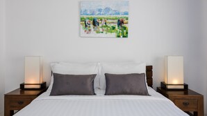 A bedroom with a bed, two bedside tables with lamps, a painting on the wall, and a nightstand with a drawer. - Modern Tropical Villa (Koh Samui)