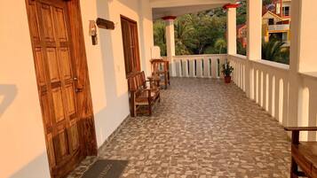 A covered outdoor area with a tiled floor, wooden benches, and a door.
