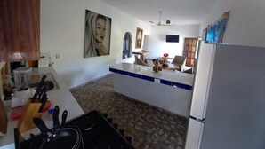 A kitchen with a central island, a refrigerator, and a dining area with chairs. - Casa El Delfin, 2nd Floor-Apt. 1 -  Estacahuite (Estacahuite)