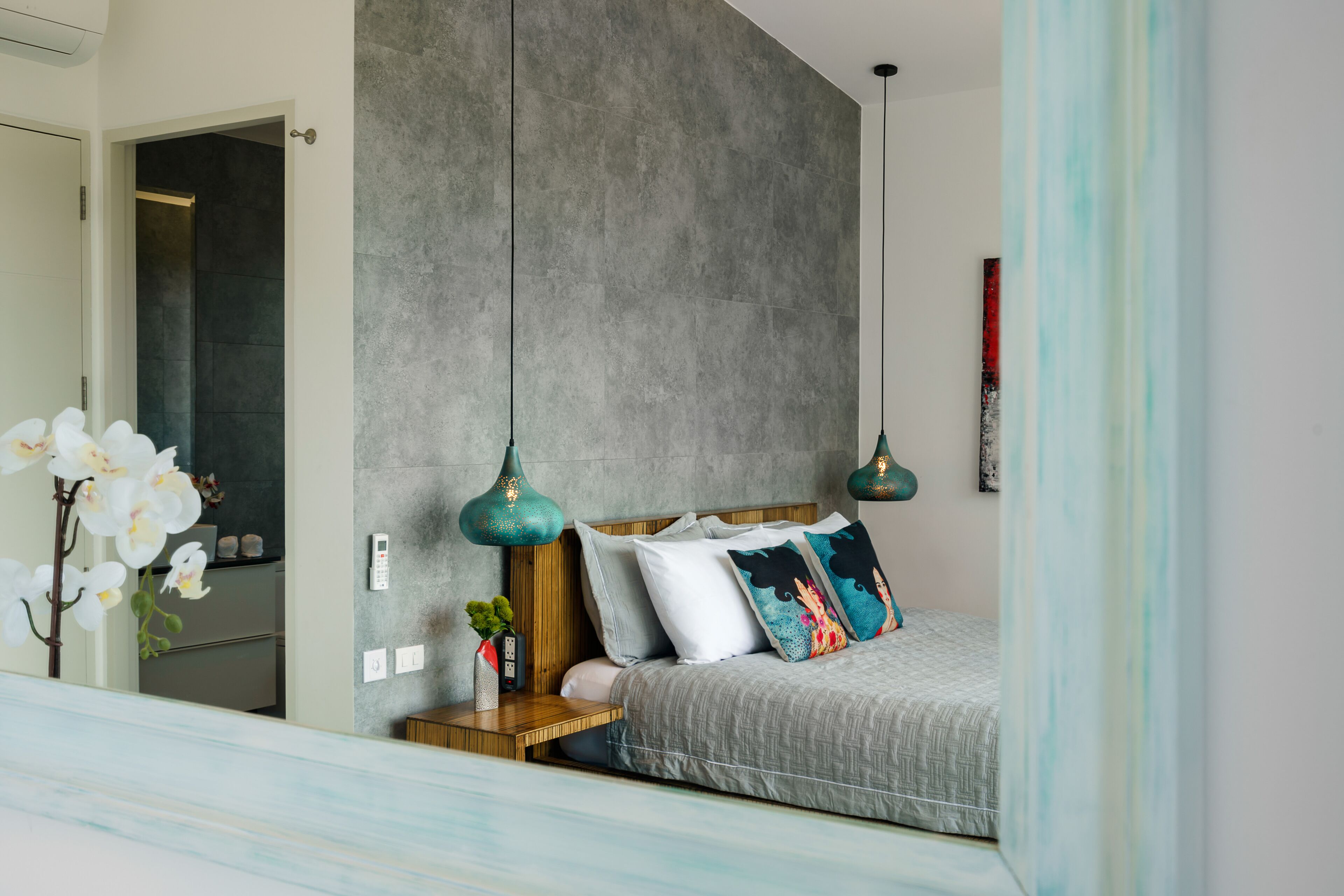 Een slaapkamer met een bed, nachtkastje en een telefoon aan de muur.